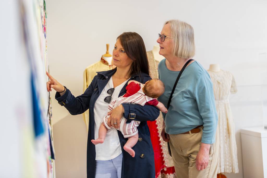 Skipton Town Hall_168 Two women look at the gallery display. One of them is holding a baby.