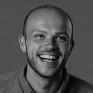 Joel 2 Black and white image of a man with shaven head and short beard. He is smiling.