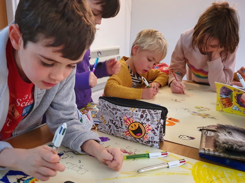 Make & Take Web 02 Four children drawing pictures on large pieces of paper.