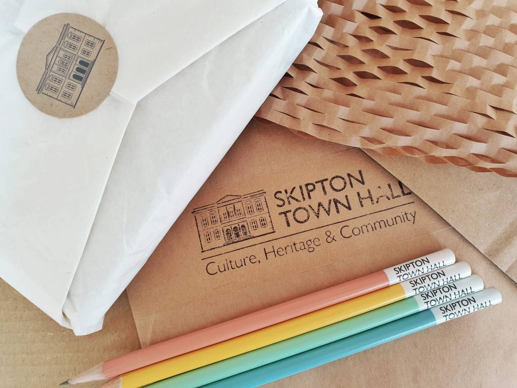 Packaging brown and white paper packaging with the Skipton Town Hall brnding and some coloured pencils.
